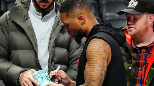 Damian Lillard signs a fan's shoe before a game.